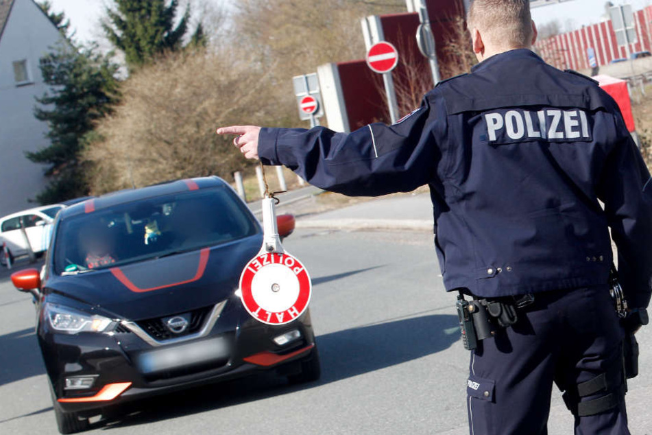 Ein Polizist winkt ein getuntes Auto beim großen Tuning-Treffen in Bochum zur Kontrolle heraus.