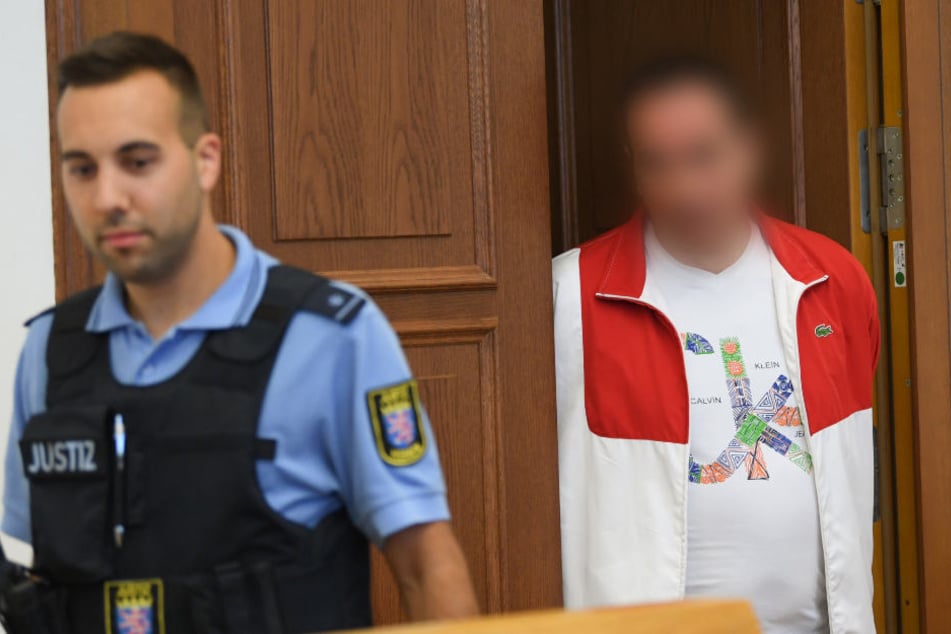 Der Angeklagte betritt in Begleitung eines Justiz-Beamten den Gerichtssaal.