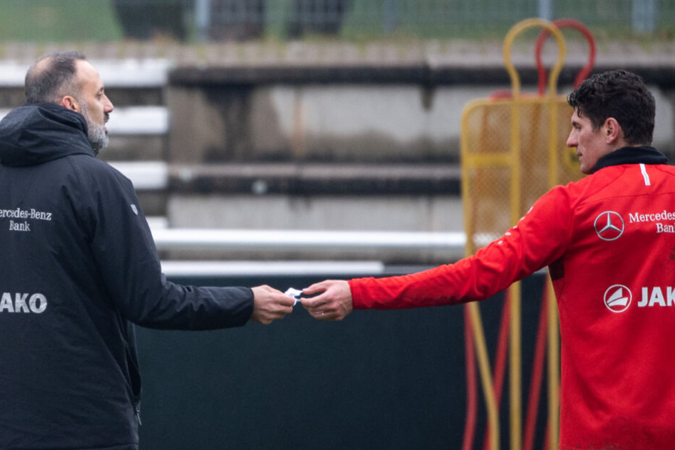 Pellegrino Matarazzo (l), Trainer des VfB Stuttgart, nimmt von Mario Gomez einen Zettel entgegen.
