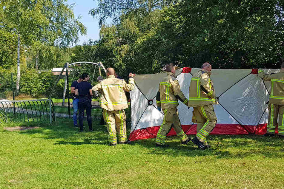 Rettungskräfte stellen eine mobile Absperrwand an einem Spielplatz auf, auf dem der Mann getötet wurde.