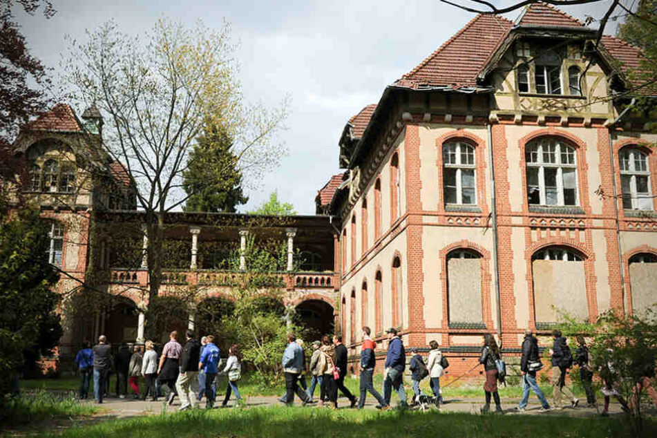 Eine Besuchergruppe geht an der ehemaligen Chirurgie auf dem Gelände der Beelitz-Heilstätten in Beelitz (Brandenburg) entlang.