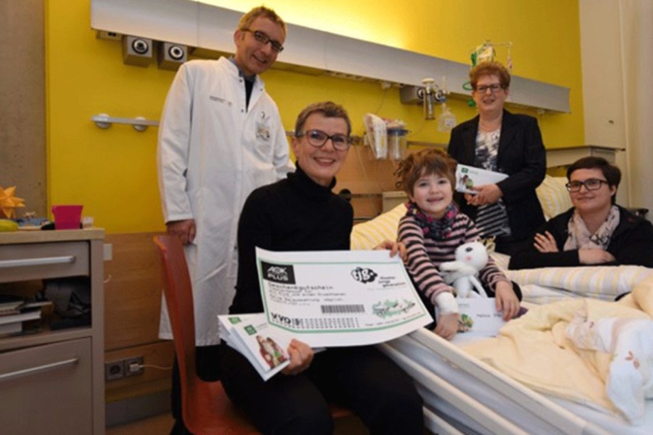 AOK Plus-Sprecherin Hannelore Strobel (vorn) bringt der kleinen Melissa Hille (5) Theaterkarten ans Krankenbett.