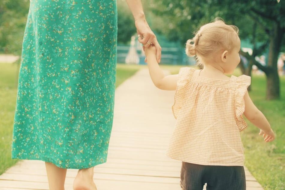 Eine Mutter geht mit ihrer jungen Tochter an der Hand (Symbolbild).