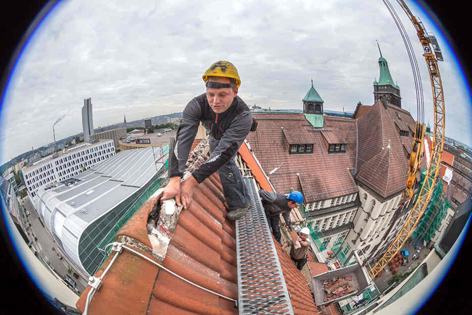 Herunter mit den alten Ziegeln! Dachdecker Nico Zimmermann (33, l.) entfernt
mit seinen Kollegen alte Ziegel auf der Dachspitze. Rechts davon liegen bereits
die neuen in Naturrot.