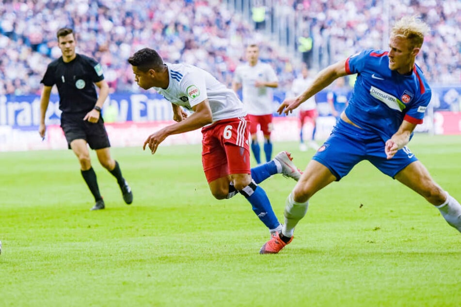 Hamburgs Douglas Santos (M) setzt sich gegen Heidenheims Sebastian Griesbeck (r) durch.