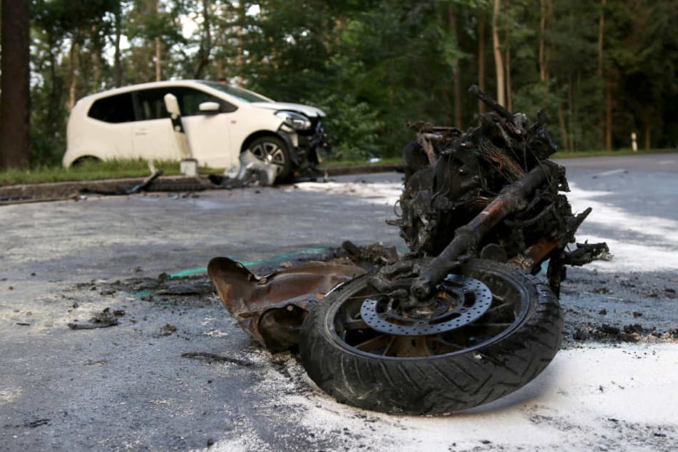 Ein verbranntes Motorrad liegt neben einem zerstörten Fahrzeug auf der L1147.
