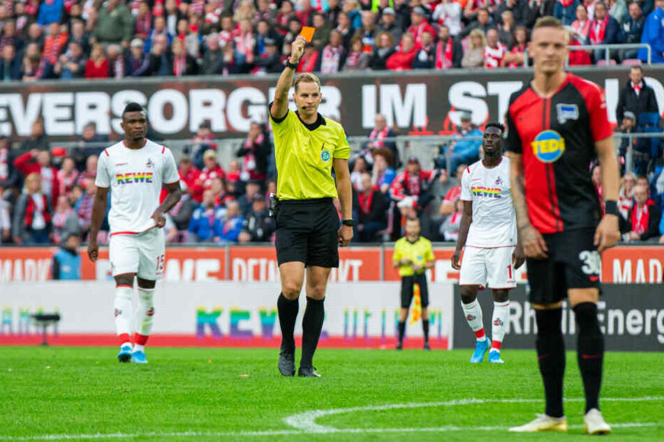Schiedsrichter Sören Storks (M) zeigt nach Ansicht der Videobilder J. Meré (Nicht im Bild) von Köln die rote Karte.