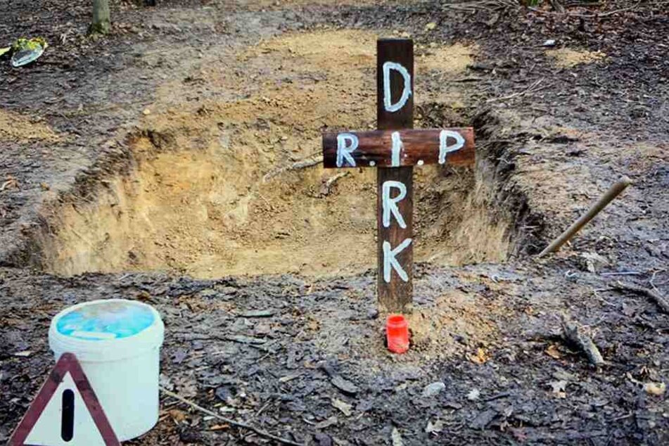 Dieses im Januar aufgenommene und von der Polizei zur Verfügung gestellte Foto zeigt eine Grube mitten im Hambacher Forst, davor ein Kreuz mit der Inschrift "R.I.P. Dirk".