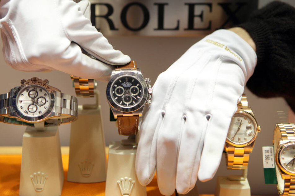 Mit weißen Handschuhen werden Uhren der Schweizer Marke Rolex in einem Schaufenster platziert.