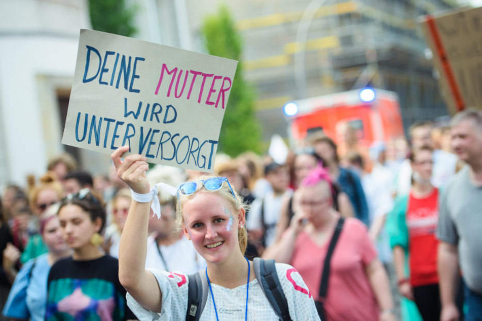 Eine Teilnehmerin hält auf der Demonstration ein Schild mit der Aufschrift "Deine Mutter wird unterversorgt".