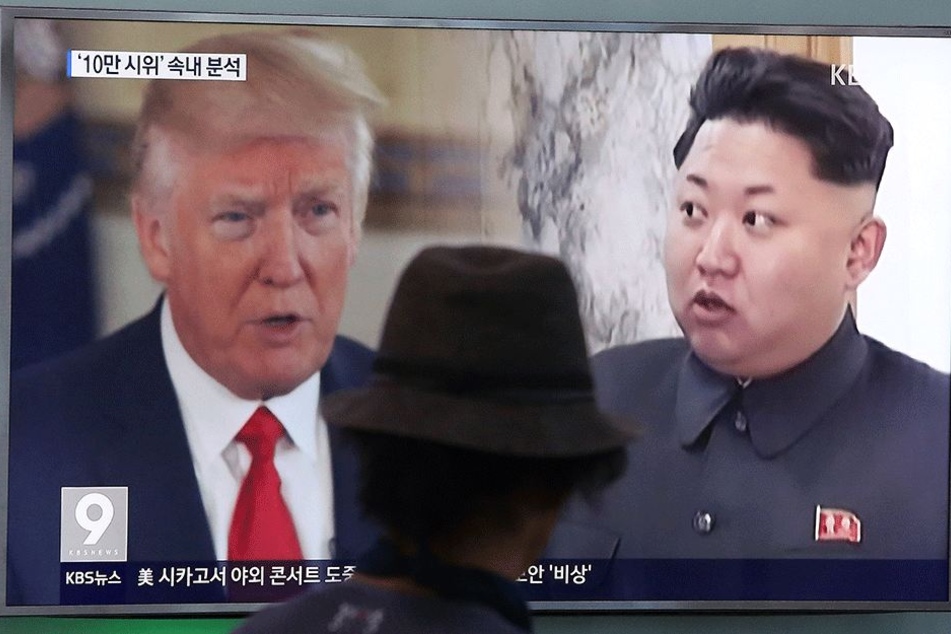 Ein Mann blickt am 10. August in einer Bahnstation in Seoul (Südkorea) auf einen Bildschirm, auf dem von einem Nachrichtensender Bilder von Nordkoreas Staatschef Kim Jong Un (r) und US-Präsident Donald Trump (71) gezeigt werden.