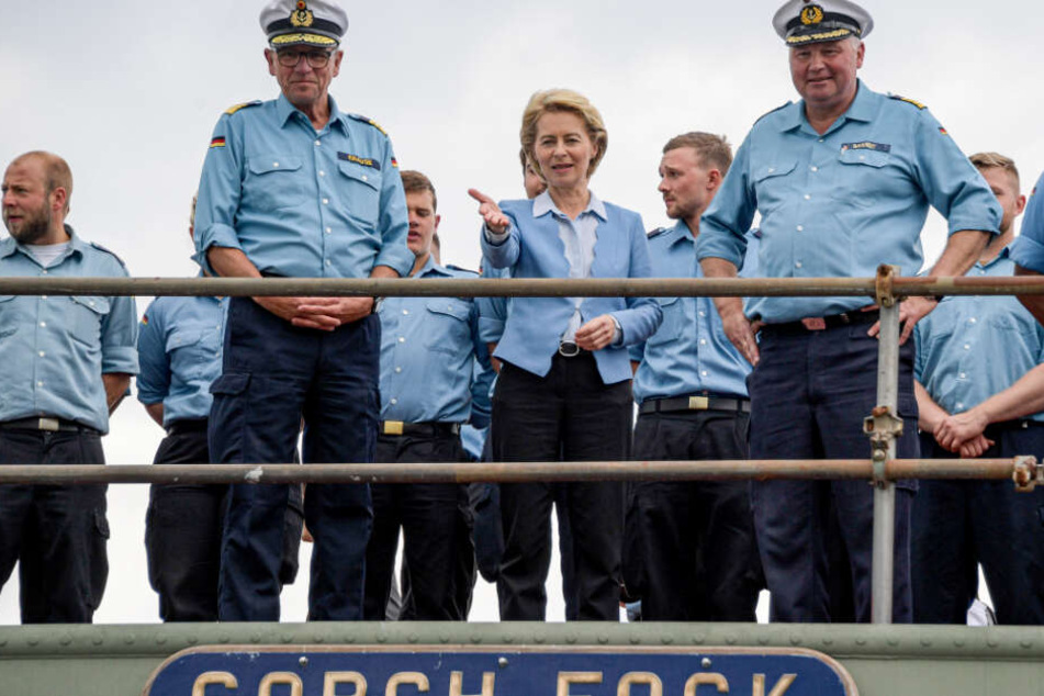 Ursula von der Leyen steht gemeinsam mit der Besatzung an Bord.