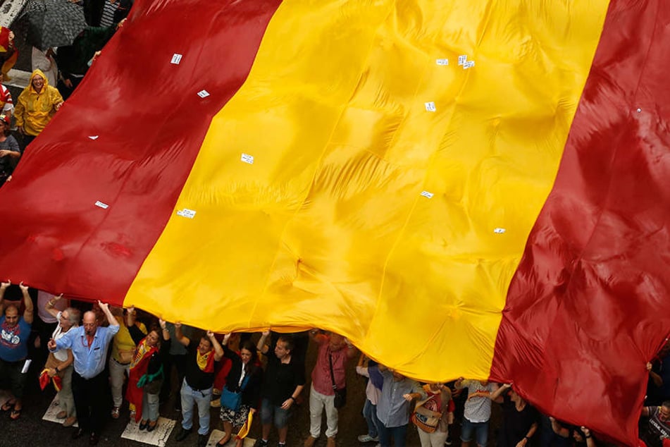 Demonstranten tragen in Barcelona (Spanien) bei einer Demonstration gegen die Unabhängigkeit Kataloniens eine riesige spanische Flagge.