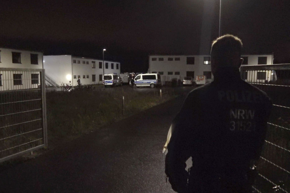 Ein Polizist steht am Tor zu einer Flüchtlingsunterkunft in dem Ort.