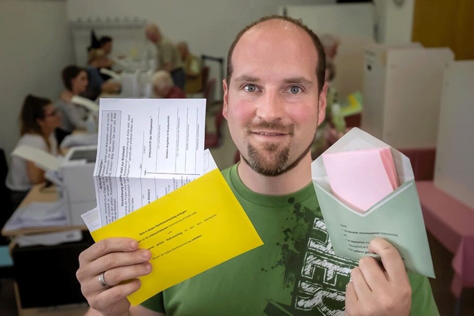 Briefwahlchef Matthias Schieck (37) zeigt die Umschläge: Grün für den Wahlzettel, gelb für die Versicherung.