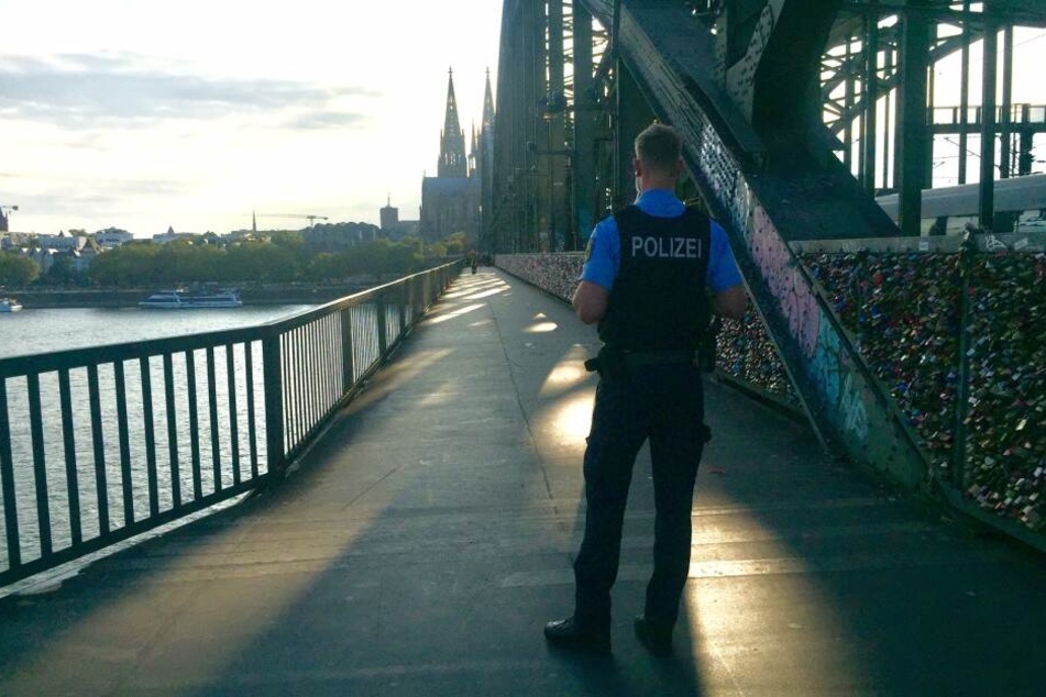 Ein Polizeibeamter bewachte die abgesperrte Hohenzollernbrücke. Der Bahnverkehr wurde nicht gestoppt.