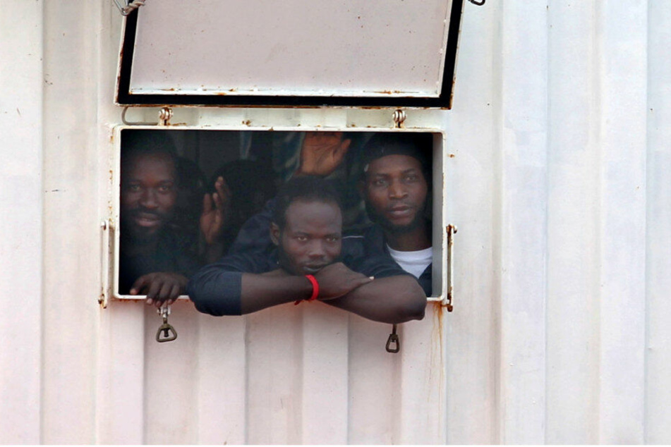 Migranten blicken aus der Öffnung eines Containers an Bord eines Rettungsschiffes. (Archivbild)