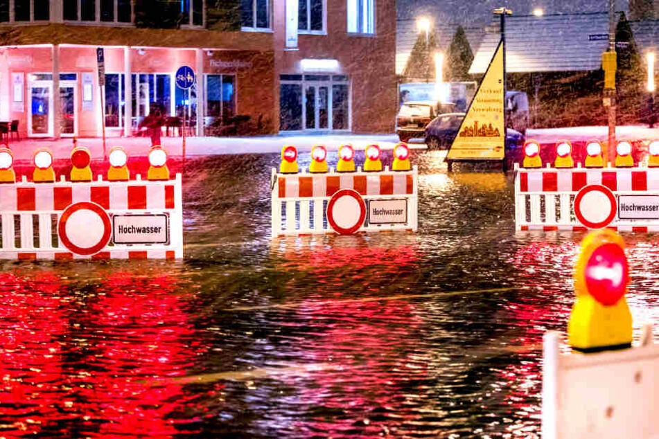Absperrungen stehen in Wismar auf einer
überfluteten Straßenkreuzung am Stadthafen.