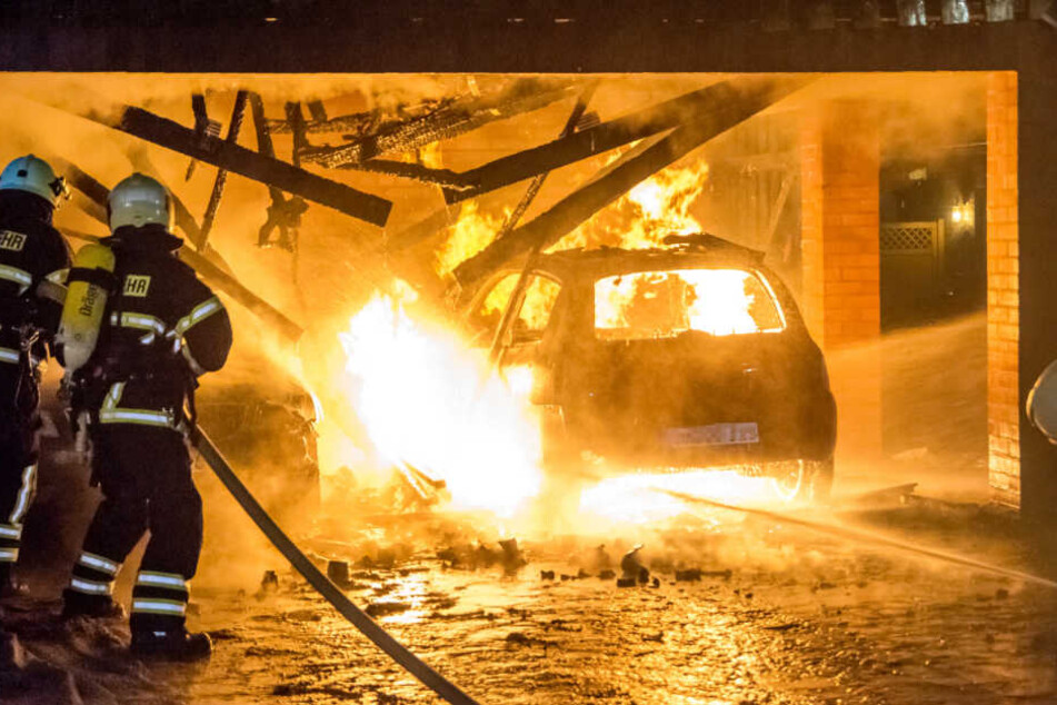 Carports und Auto stehen lichterloh in Flammen. Die Feuerwehr versucht den Brand zu löschen.