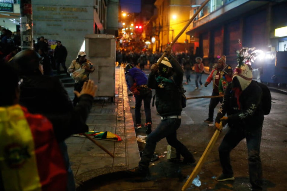 Mit einem Stock versucht ein Anhänger von Präsident Morales auf einen Demonstranten einzuschlagen.