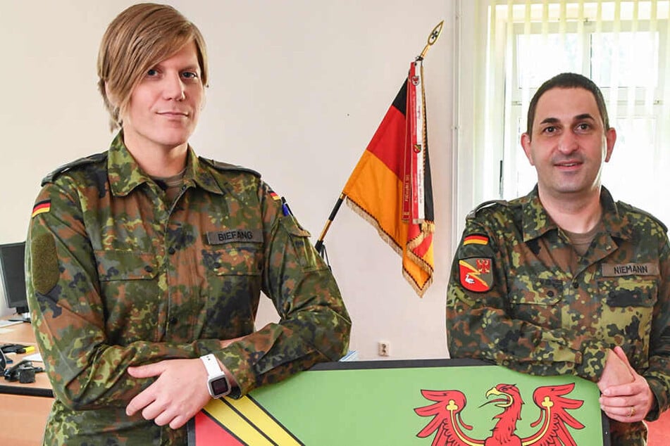 Ein ehemaliger Oberstleutnant (rechts) und seine Nachfolgerin stehen vor dem Wappen der Kurmark-Kaserne.