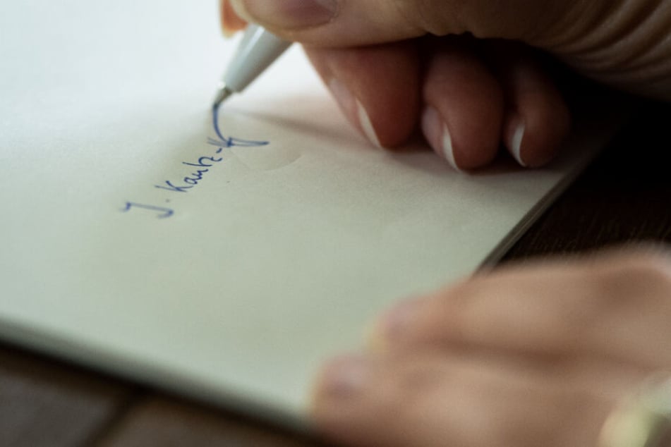 Eine Frau setzt ihre Unterschrift. (Symbolbild)