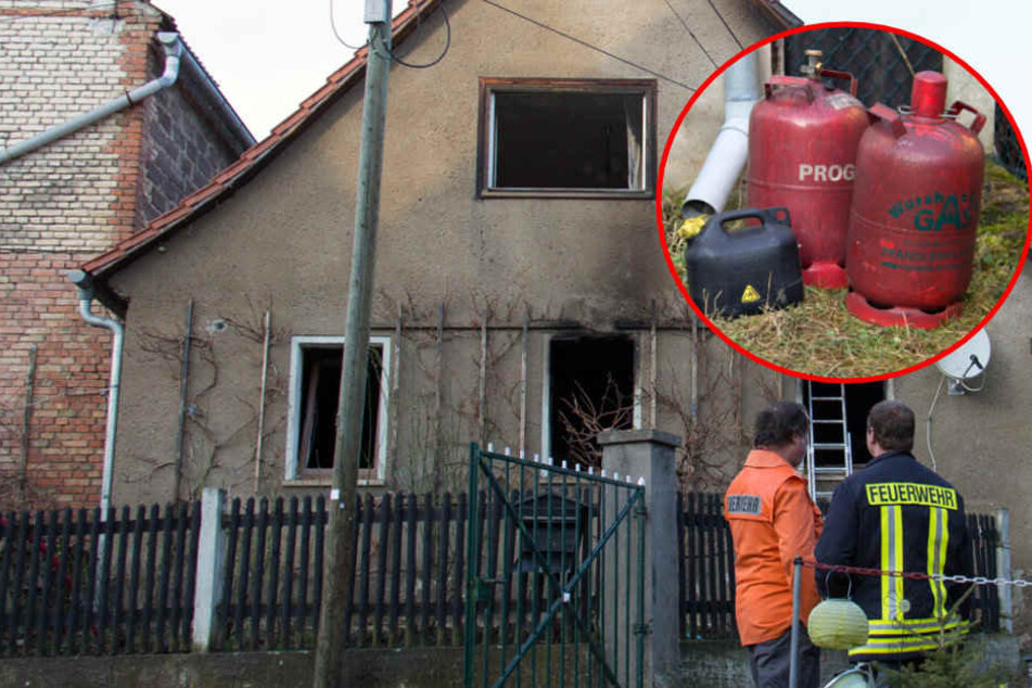 Einsatzkräfte der Feuerwehr stehen vor dem ausgebrannten Gebäude.