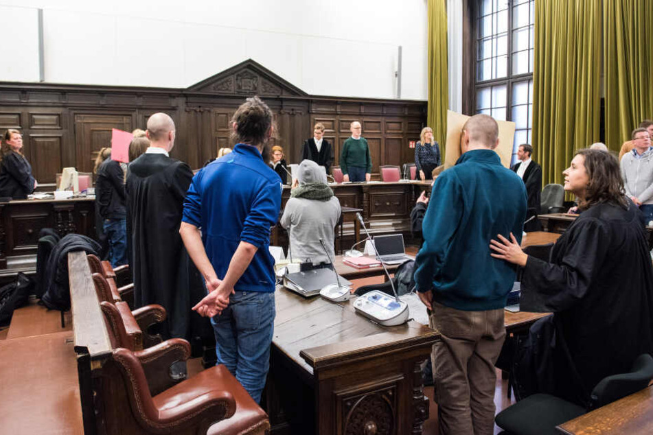 Drei Angeklagte stehen mit ihren Anwälten im Landgericht.