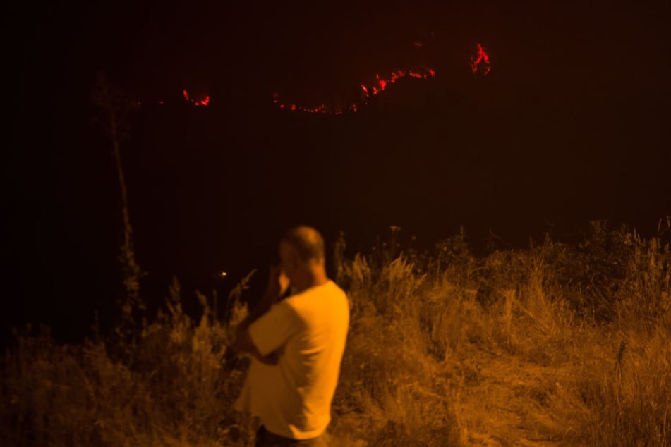 Ein Anwohner beobachtet in Casalinho von einem Hügel aus ein circa 300 Meter entferntes Feuerband, das sich unweit des Dorfes entlang zieht.