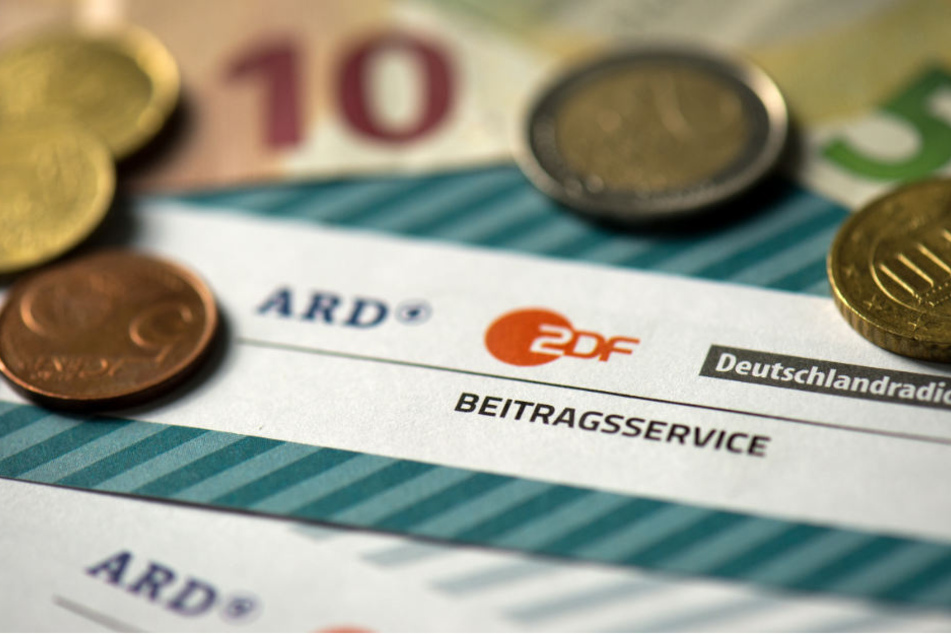 Münzgeld liegt auf Formularen für den Rundfunkbeitragvon ARD, ZDF und Deutschlandradio.