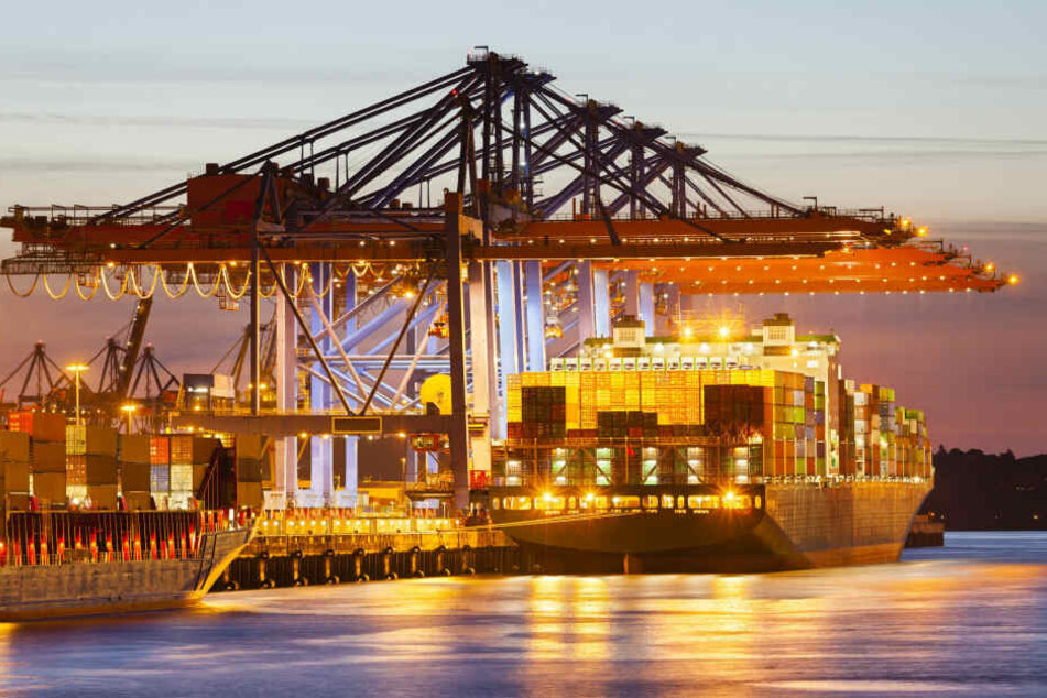 Ein Containerschiff liegt in der Abenddämmerung an einem Hamburger Terminal.