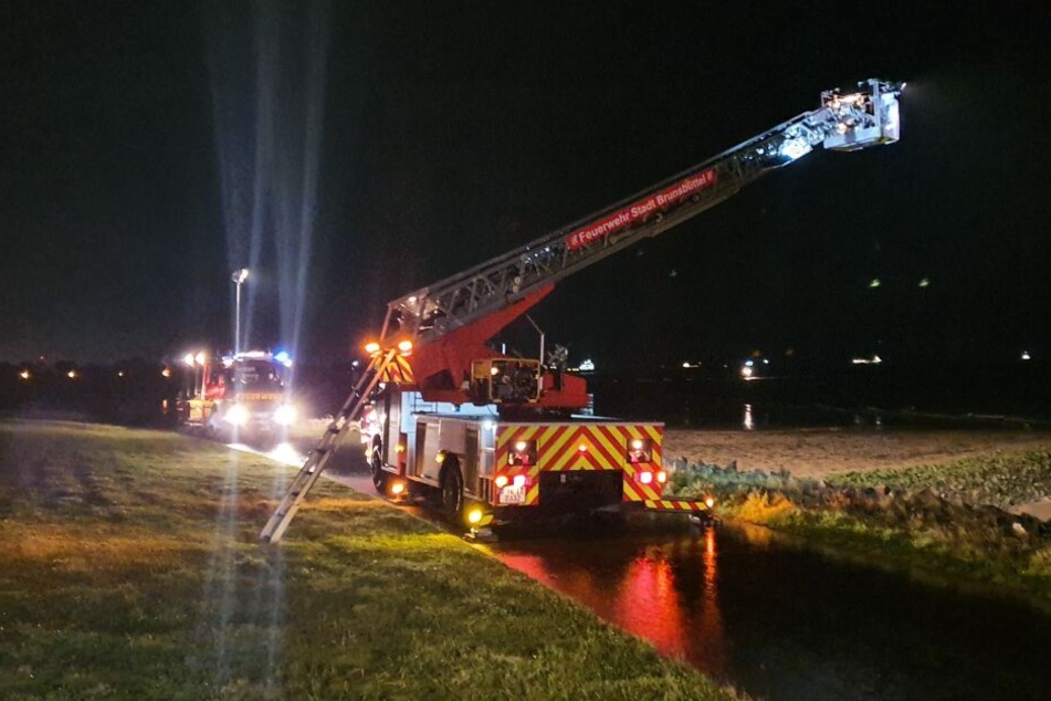 Feuerwehrfahrzeuge stehen an einem Deich bei Brunsbüttel und suchen nach der Mutter und ihrem Sohn.