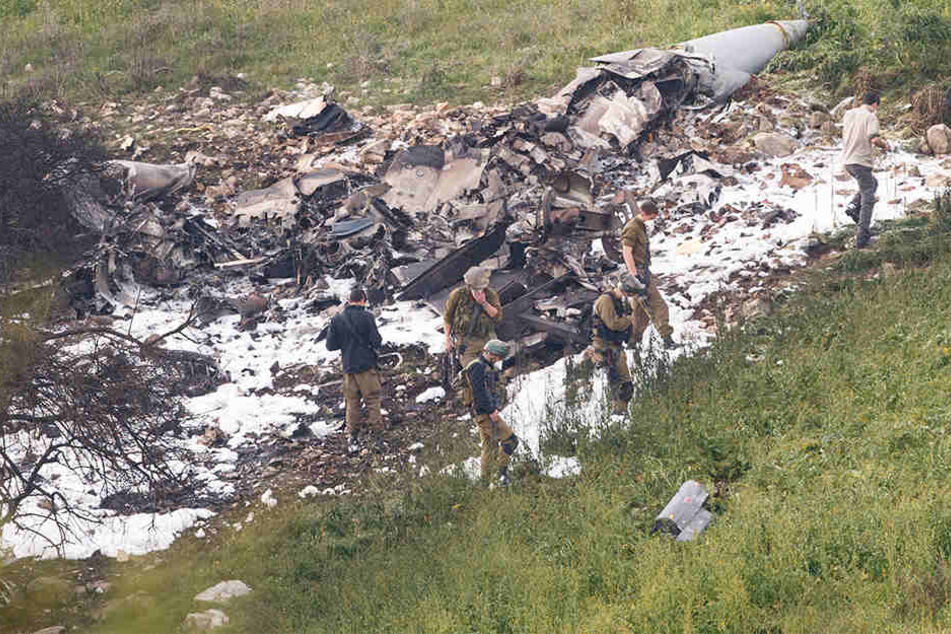 Israelische Sicherheitskräfte stehen am 10.02.2018 neben den Überresten eines israelischen F-16 Kampfflugzeugs an der Absturzstelle bei Harduf.