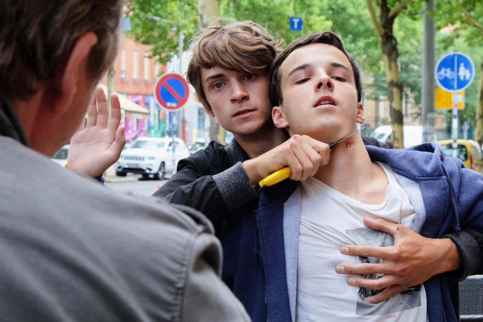 Jonas Heilmann (Anthony Petrifke, r.) ist zufälligerweise in einem Lebensmittelgeschäft, als dieses überfallen wird. Als der Täter (Tamino Haberland, Mitte) fliehen will, kann Jonas nicht anders und versucht ihn aufzuhalten. Die Aktion missglückt.