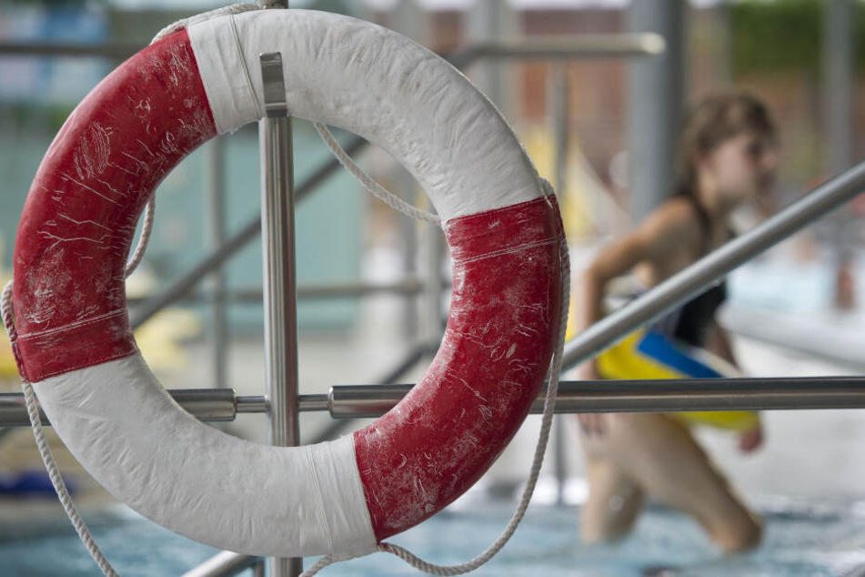Ein Kind mit Schwimmring geht an einem Rettungsring vorbei. Immer weniger Kinder können sicher Schwimmen.