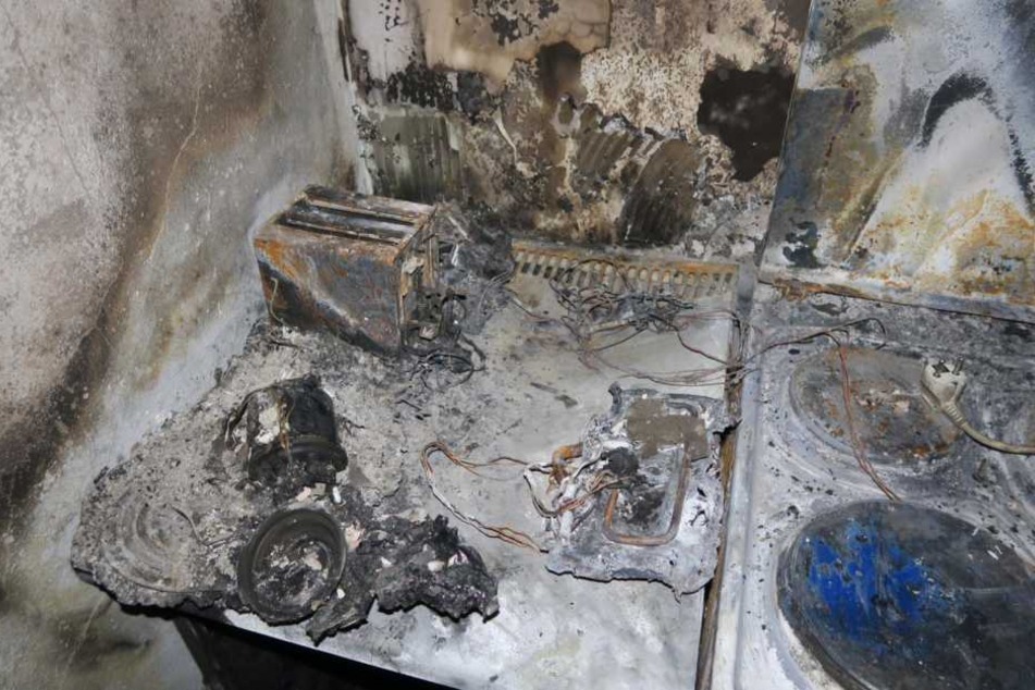 Auf einer Herdplatte liegt der Stecker einer Verteilersteckdose (r.). Sie soll Auslöser des verheerenden Brandes gewesen sein.