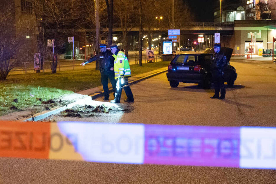 Das Fluchtauto fuhr über einen Grünstreifen und blieb dann auf der Straße stehen. Polizisten untersuchen die Spuren und sehen sich den Schaden an.