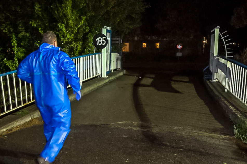 Ein Mann im blauen Ganzkörperschutzanzug geht in Richtung Campingplatz.