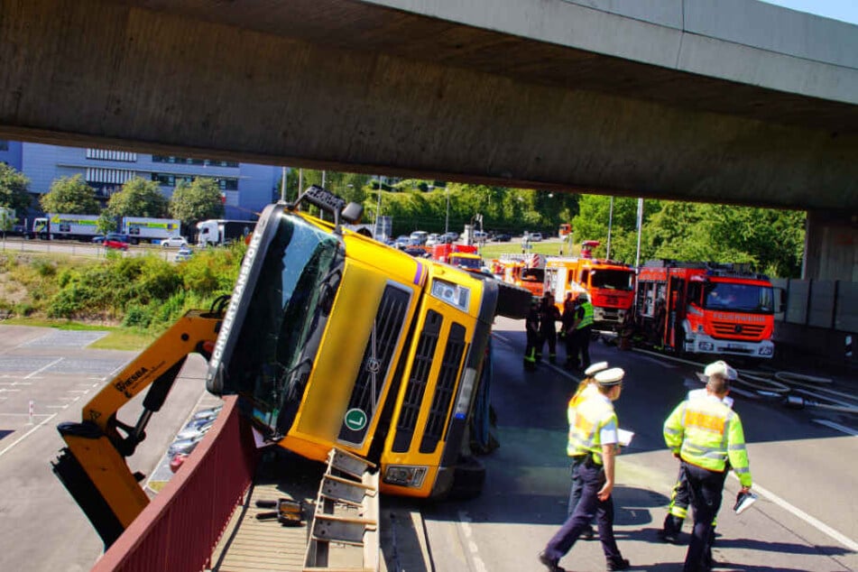 Der Unfall-Truck liegt auf der Seite, der Kran hängt über den Rand der Brücke.