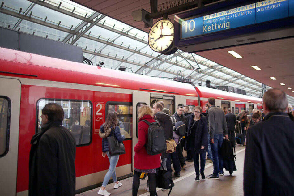 Pendler stehen an einer S-Bahn im Kölner Hauptbahnhof.