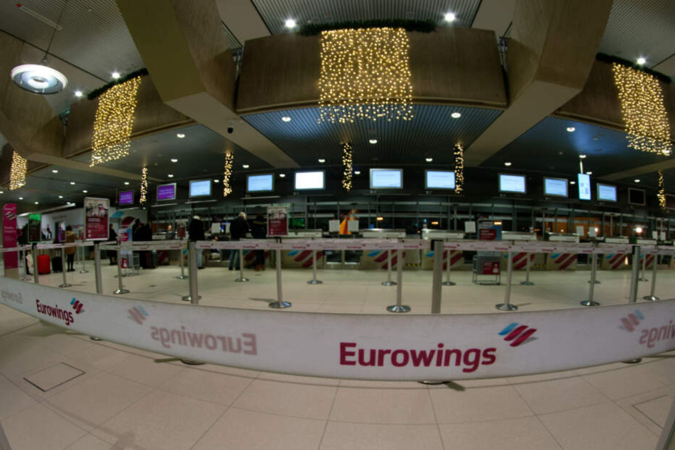 Reisende stehen am Check In Schalter der Fluggesellschaft Eurowings.