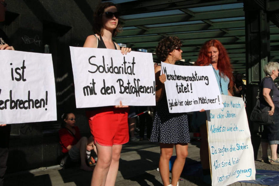 Teilnehmer der Mahnwache halten Plakate hoch.