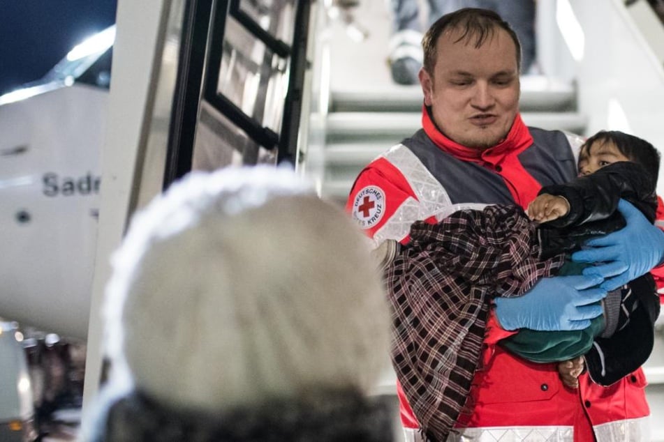 Ein kleiner schwerkranker Junge wird von Mitarbeitern des Deutschen Roten Kreuzes aus dem Flugzeug am Düsseldorfer Flughafen getragen.