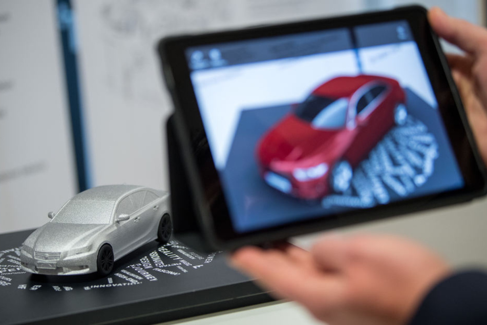 Ein Mann filmt in Stuttgart ein Automodell, um sich das Modell via augmented reality in roter Farbe anzusehen. (Archivbild)