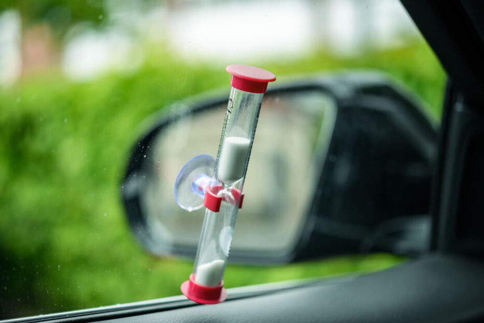 Eine Sanduhr klebt an der Innenseite eines parkenden Autos und zeigt die restliche Parkdauer an.