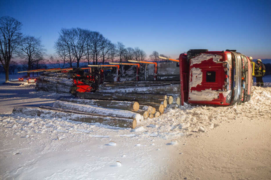 Die Holzstämme sind von dem umgekippten Laster auf das Feld gerollt.