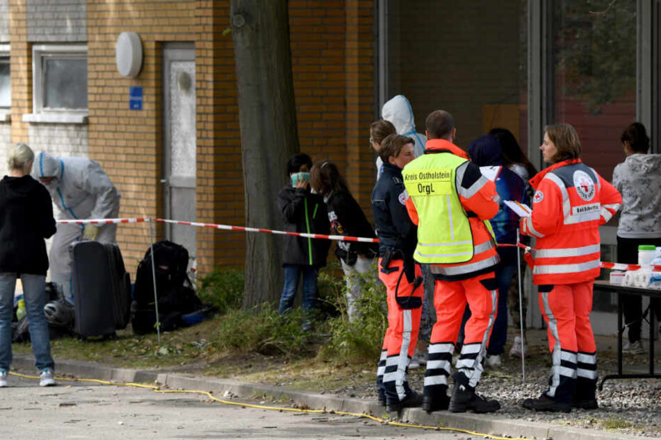 Helfer in Schutzkleidung versorgen die Kinder.