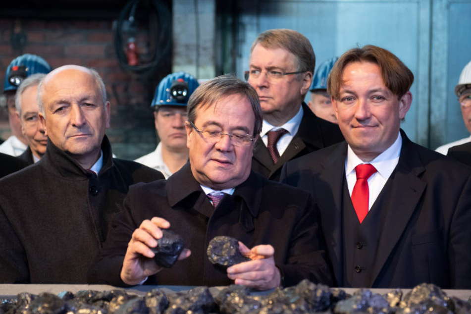 Armin Laschet (m., CDU), Ministerpräsident von Nordrhein-Westfalen, steht hinter der symbolisch letzten Lore mit Kohle.