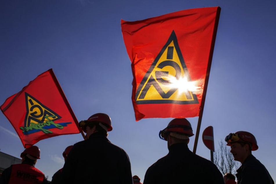 Die Fahnen der IG Metall wehen im Wind. Die Gewerkschaft schwört die Beschäftigten der sächsischen Metall- und Elektroindustrie bei den Warnstreiks am Montag auf einen harten Arbeitskampf ein.