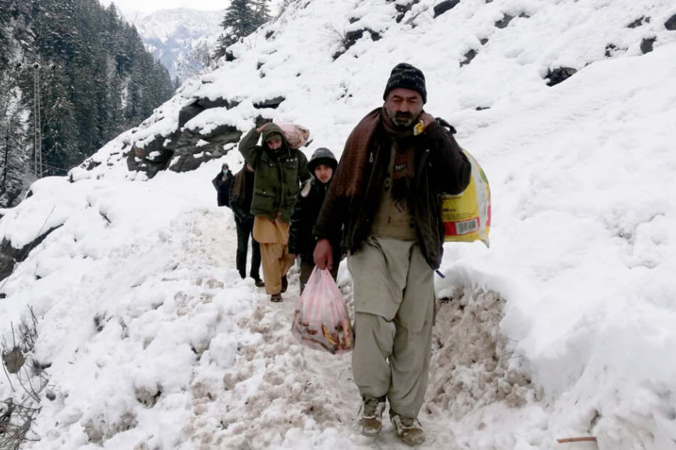 Kaschmirische Dorfbewohner gehen nach starken Schneefällen im Gebiet Neelum in der von Pakistan kontrollierten Region Kaschmir auf einem schneebedeckten Pfad.